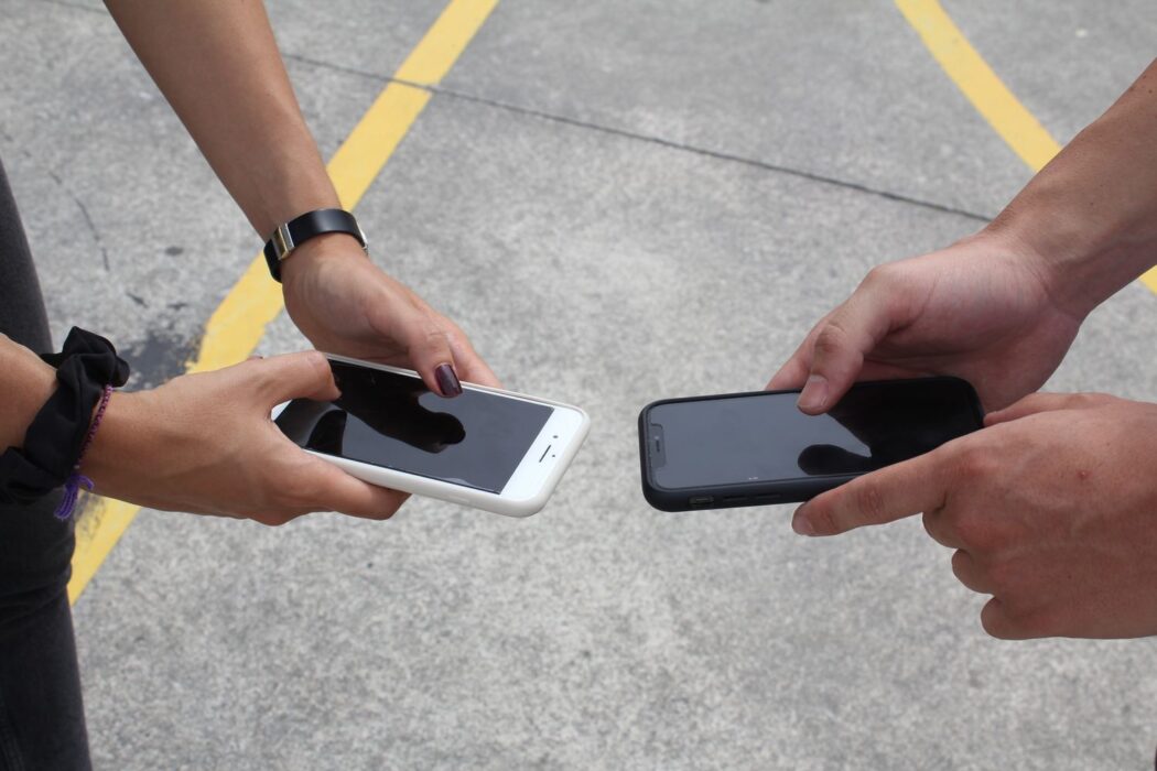 Deux personnes comparant leurs smartphones en extérieur pour parier