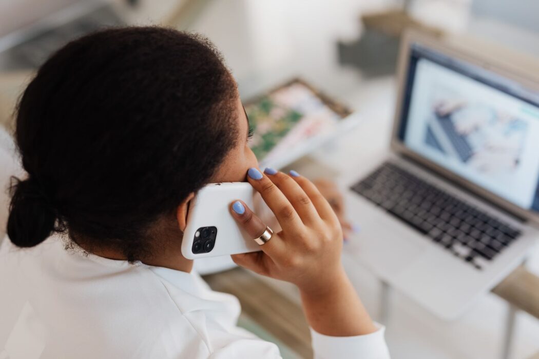 Femme au téléphone devant un ordinateur portable pour s'inscrire sur un nouveau site de paris