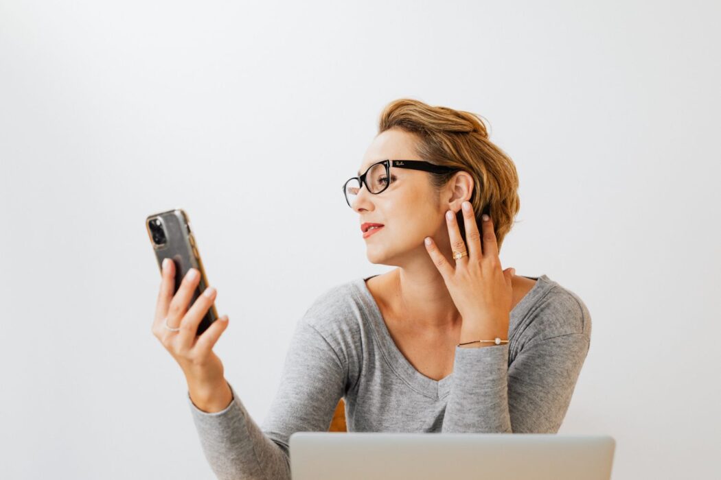 Femme portant des lunettes prenant un selfie intérieur, fond clair, pour parier