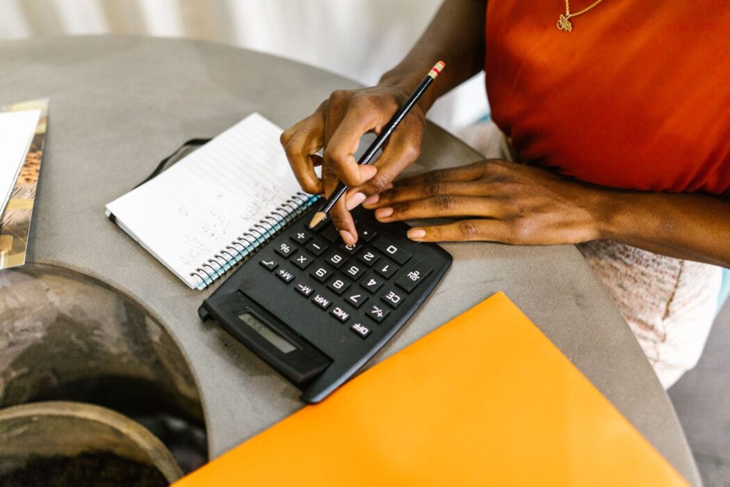 Femme utilisant une calculatrice et un carnet pour gérer son budget pari sportif