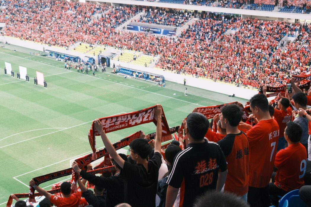Foule de supporters de football agitant des écharpes dans un stade pour parier