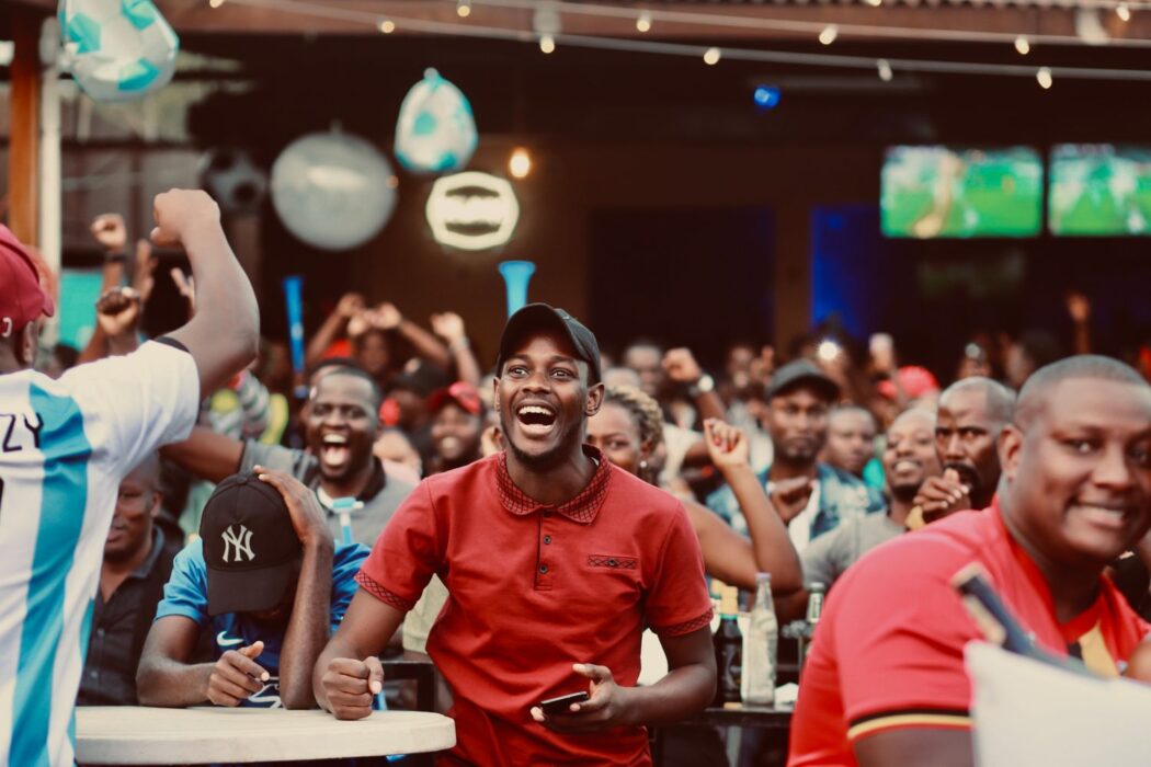 Groupe de supporters acclamant ensemble dans un bar sportif pendant un match