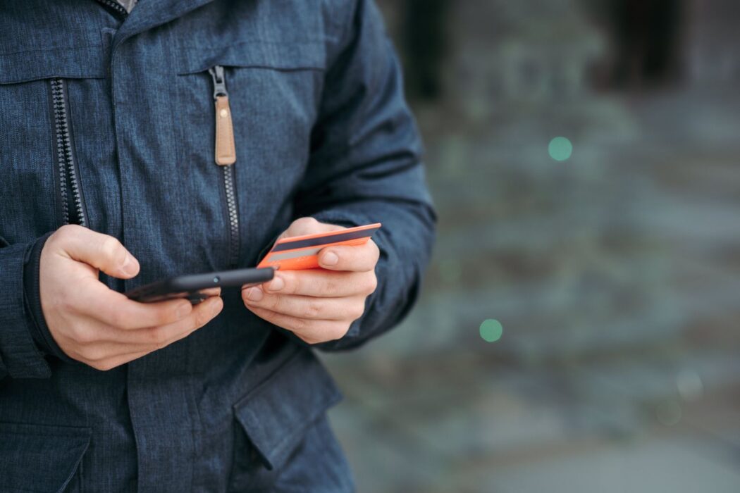 Homme dans la rue entrant les détails de sa carte bancaire sur smartphone