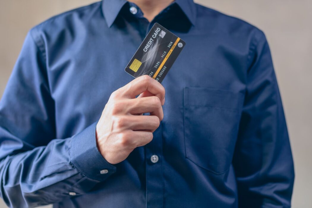 Homme en chemise bleue tenant une carte bancaire, paiement sécurisé casino en ligne