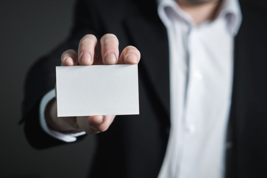 Homme en costume présentant une carte blanche pour vérification de compte Skrill