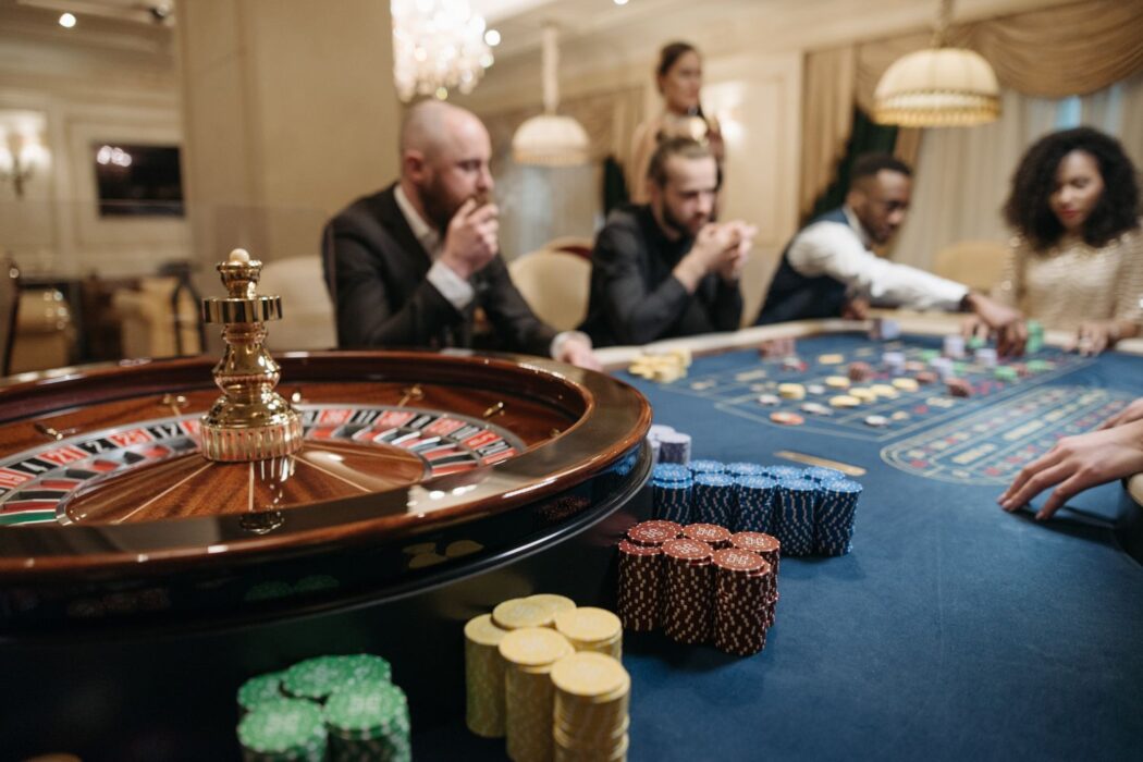 Joueurs autour d'une table de roulette avec jetons dans un casino haut de gamme