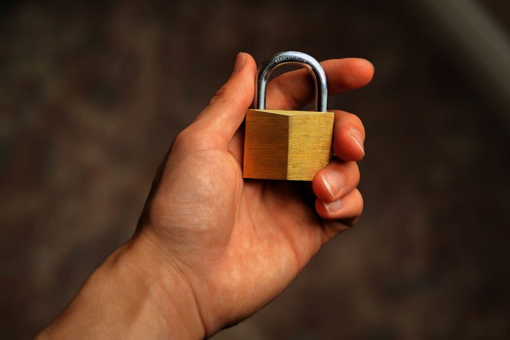 Main tenant un cadenas en laiton, symbole de sécurité en ligne