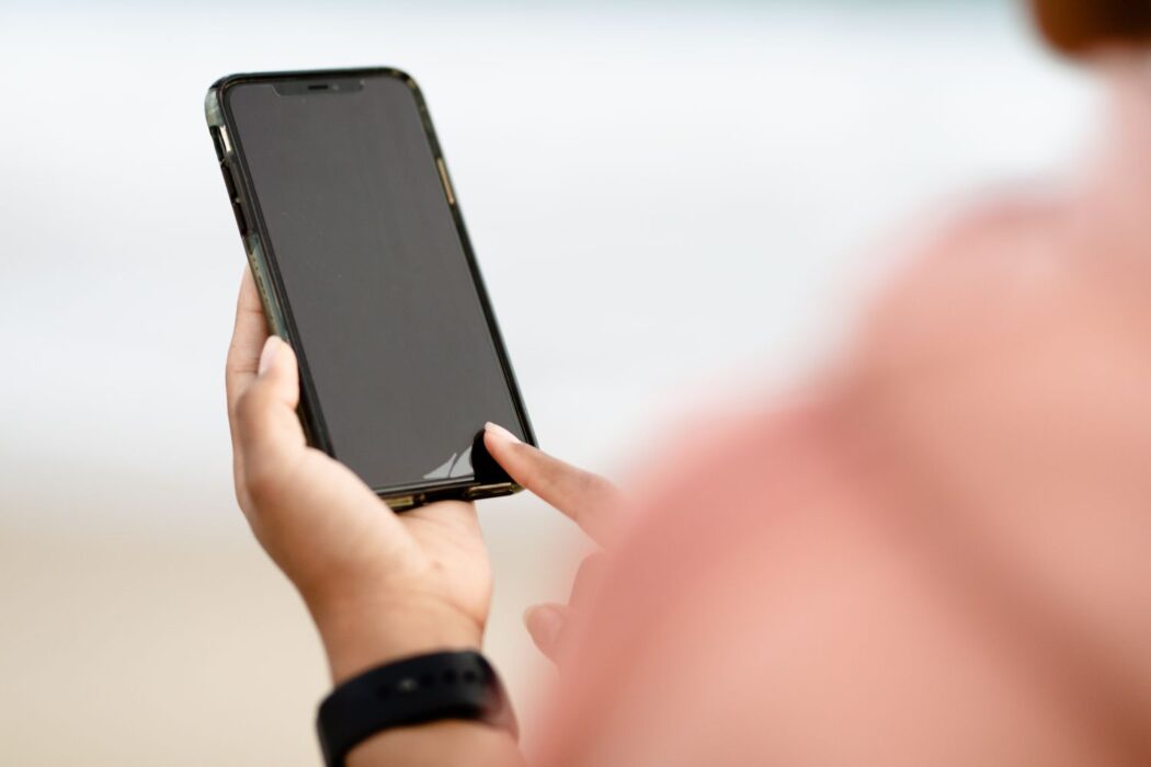 Main touchant l'écran tactile d'un smartphone en extérieur, casino mobile