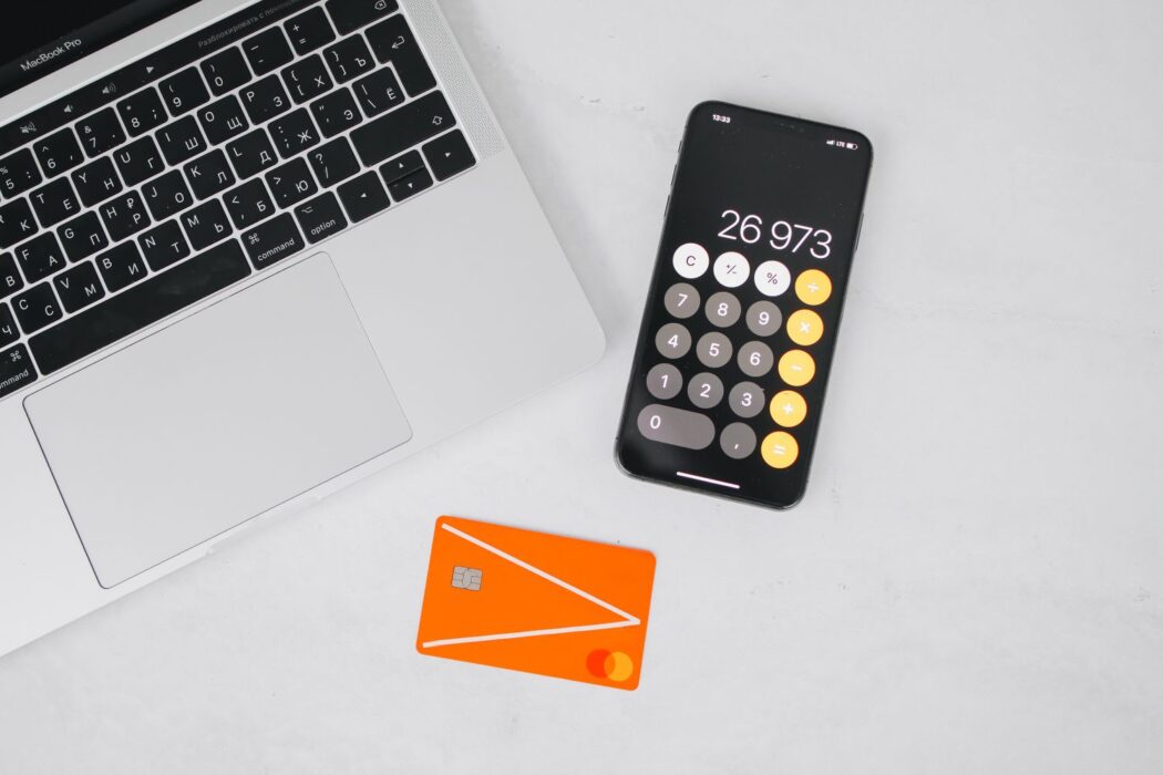 Ordinateur portable, smartphone avec calculatrice et carte bancaire sur une table blanche