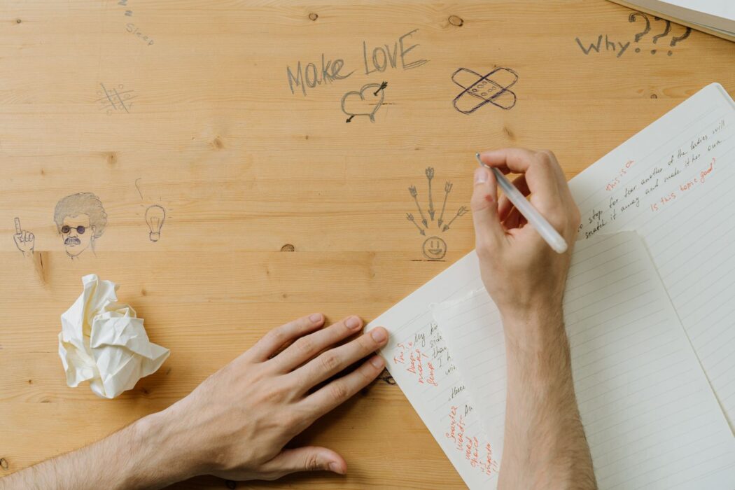 Personne écrivant des notes manuscrites sur un bureau en bois pour parier