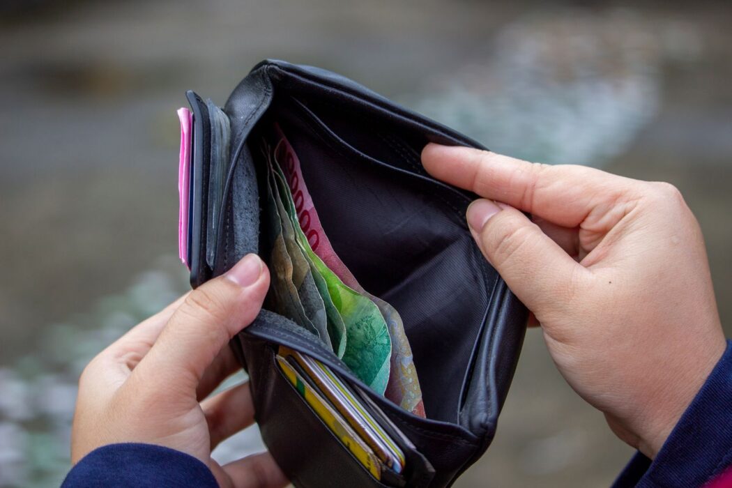 Personne tenant un portefeuille ouvert montrant des billets de banque en extérieur