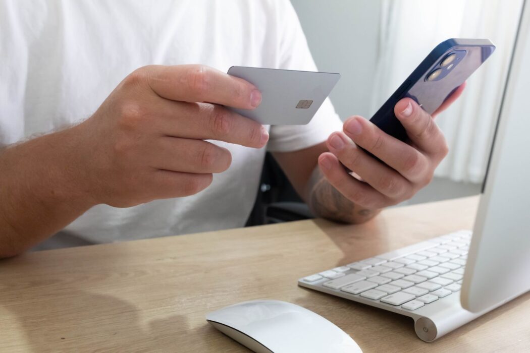 Personne tenant une carte bancaire et un smartphone sur un bureau
