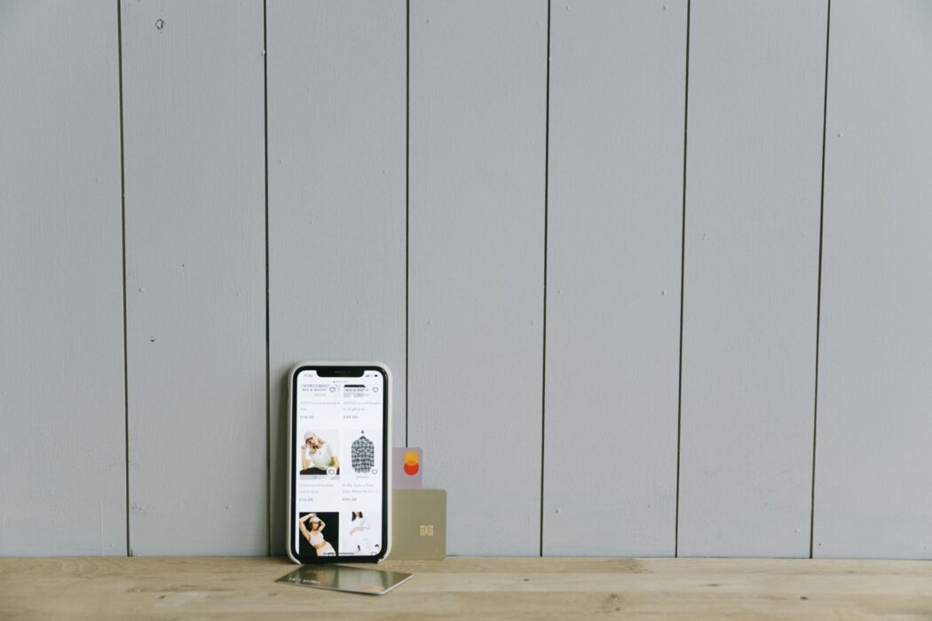 Smartphone affichant un site marchand avec une carte bancaire sur une surface en bois