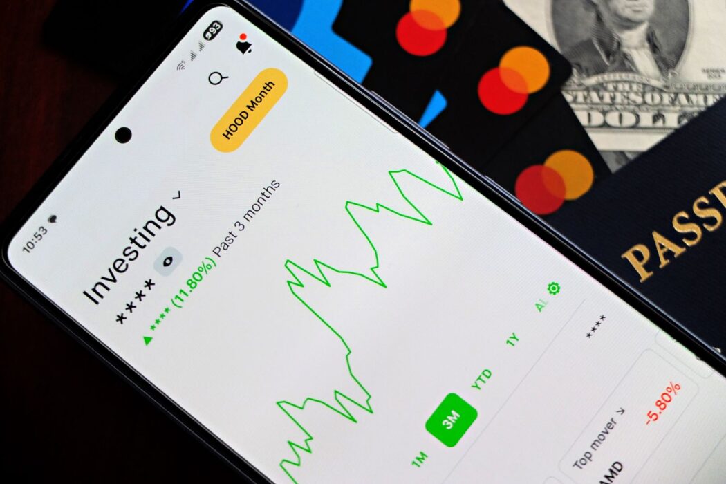 Smartphone avec indicateurs de croissance verts, entouré de cartes bancaires, billets de dollars et passeport