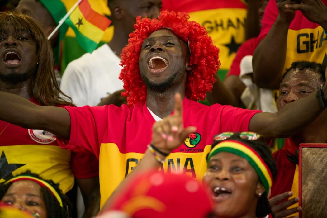 Supporters ghanéens acclamant leur équipe lors d'un match, drapeaux et maillots aux couleurs nationales